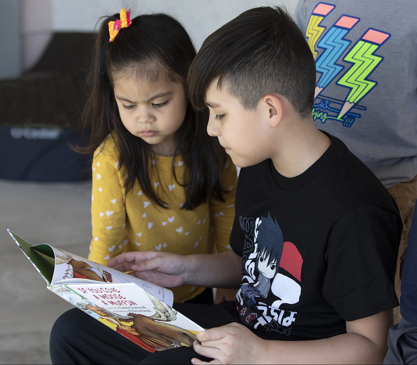 boy and girl sit together looking at a book