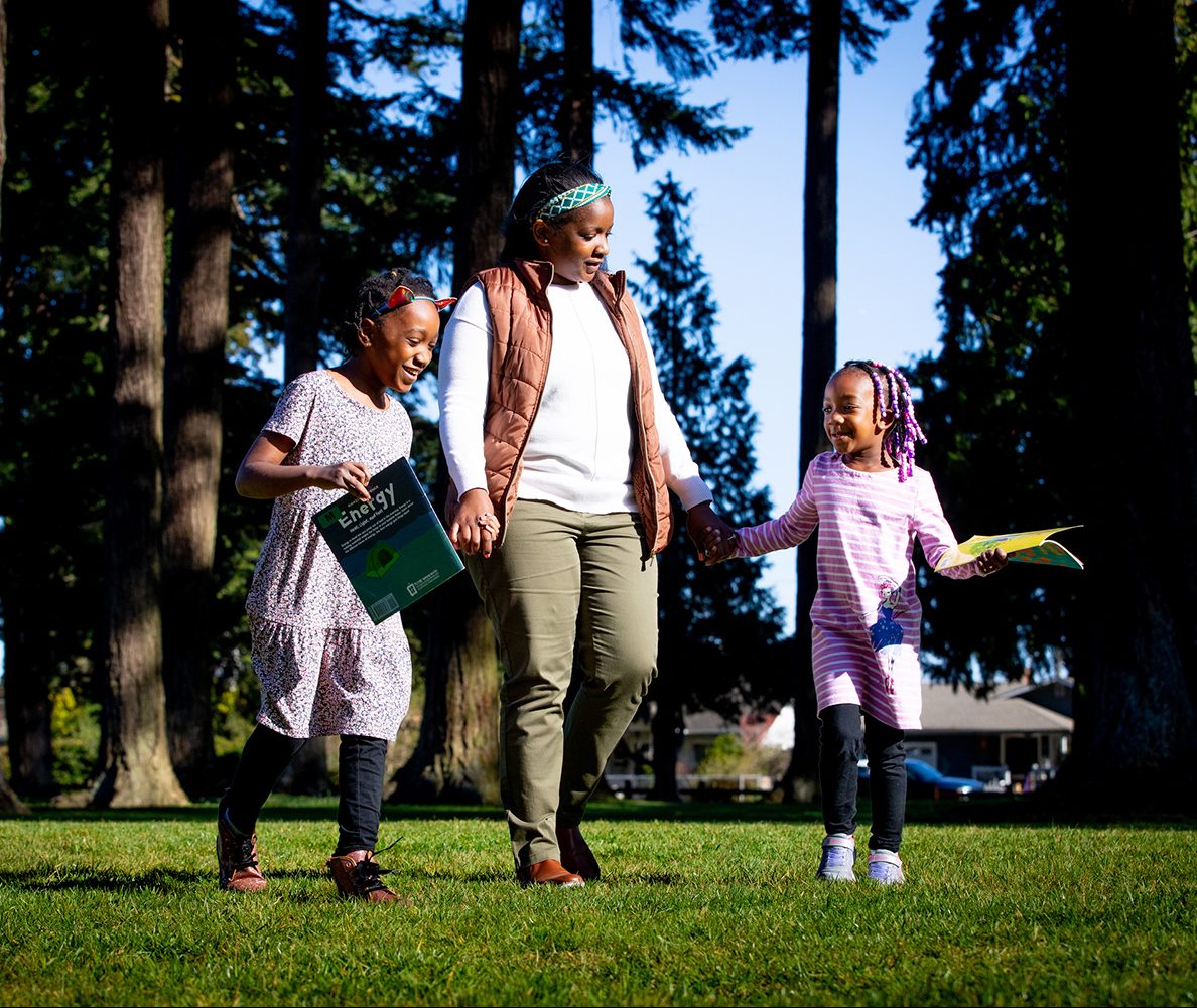 a woman walks holding hands with a little girl on each side of her