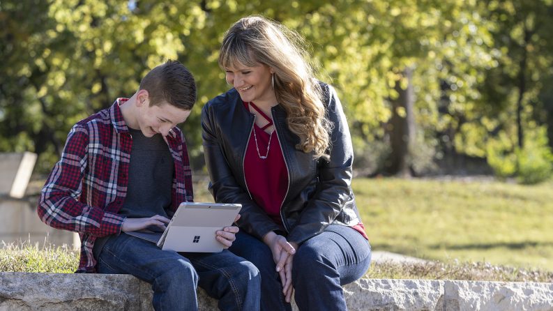 A child using a tablet with their mother sitting next to them