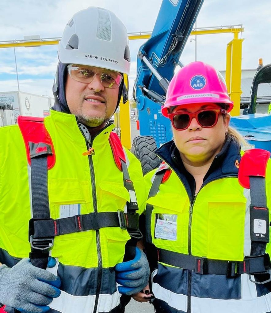 Two people standing with hard hats on