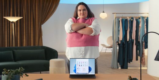 Woman standing up with arms crossed behind a laptop open to Windows 11 Start page