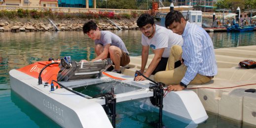 Three men from the Clearbot team make adjustments to their AI-enabled robotic boat