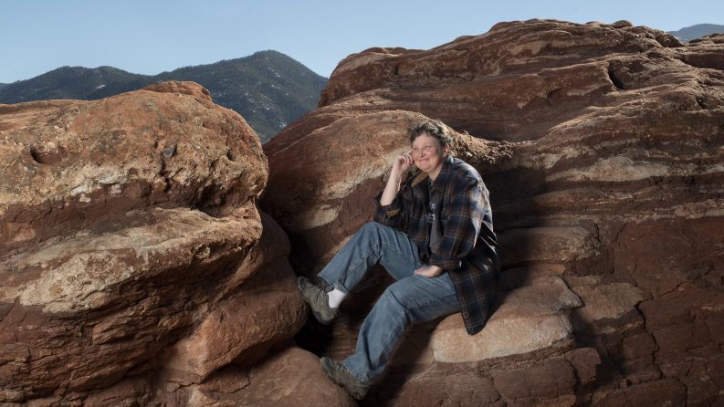 Smiling woman sitting on a rock in the outdoors