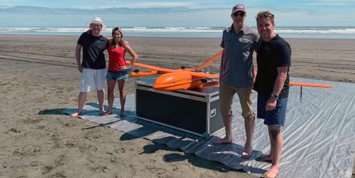 MAUI63 team of three men and a woman pose with the drone on a beach