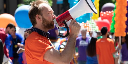 Aleksey Fedorov speaking into a megaphone at an event with people and colorful balloons in the background