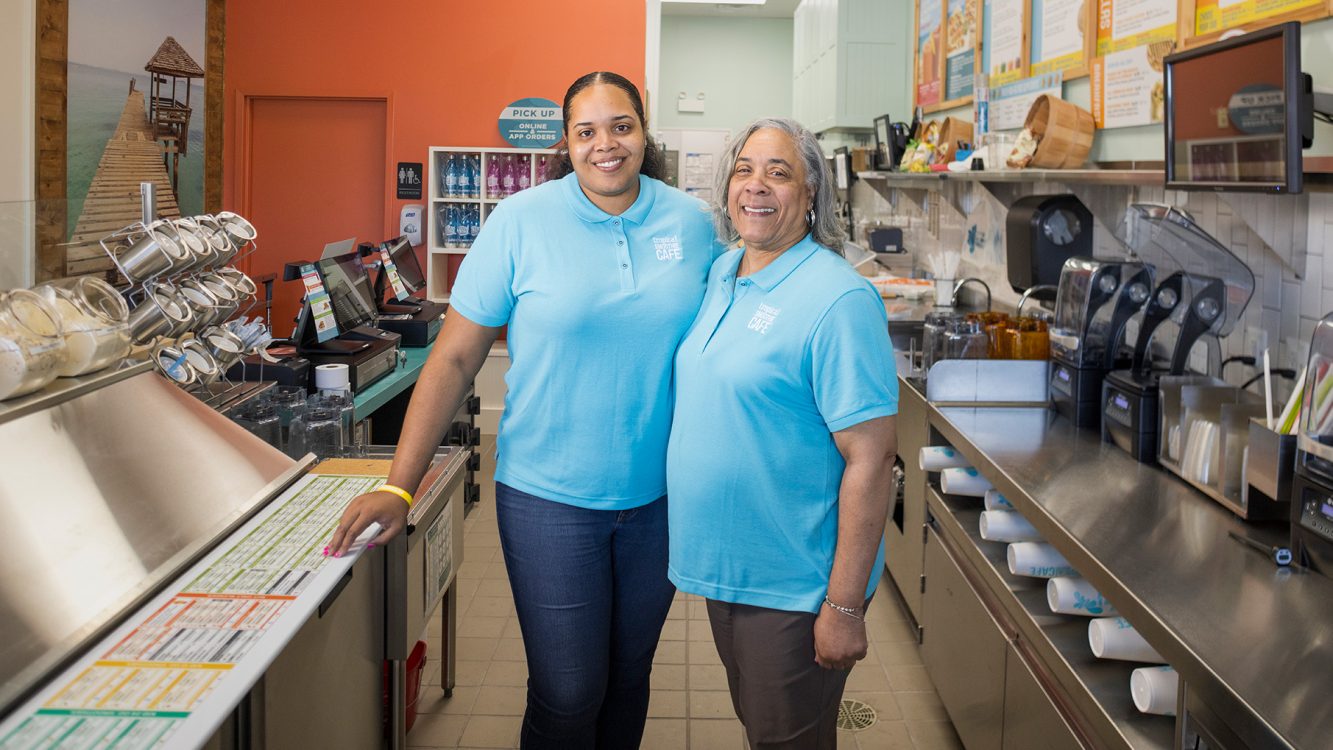 Two women stand in a kitchen smiling