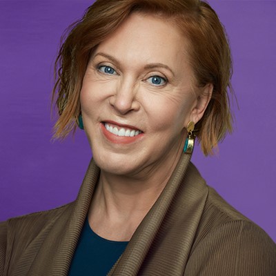 Woman smiles in front of a purple background