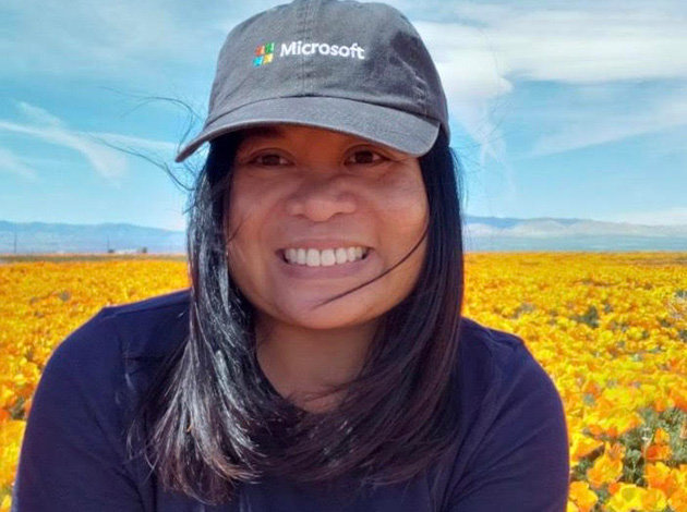 Woman smiles with hat on in field of flowers