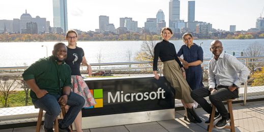 Five people sitting by a Microsoft banner with Boston in the background
