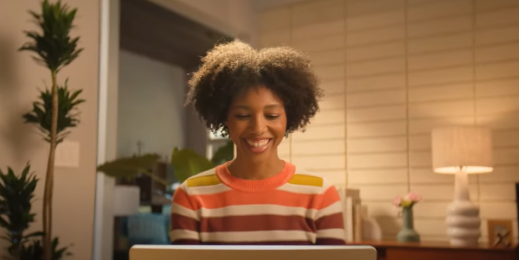 Woman working at home, smiling at what she sees on her computer