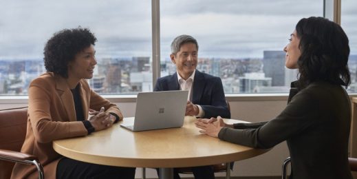 Three people meet in an office overlooking a city