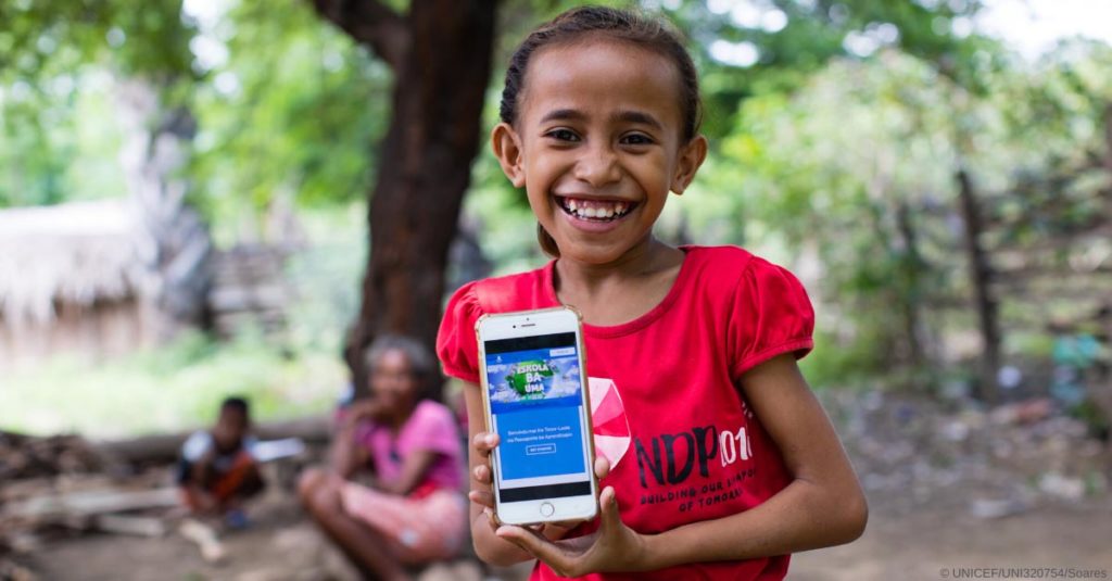 A girl smiles and presents a mobile app