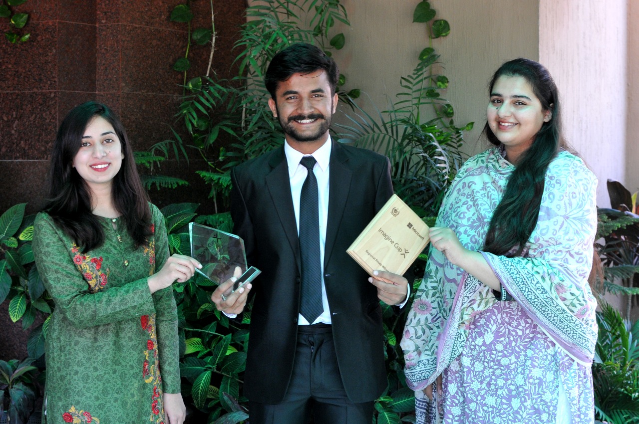 Three young people holding an award