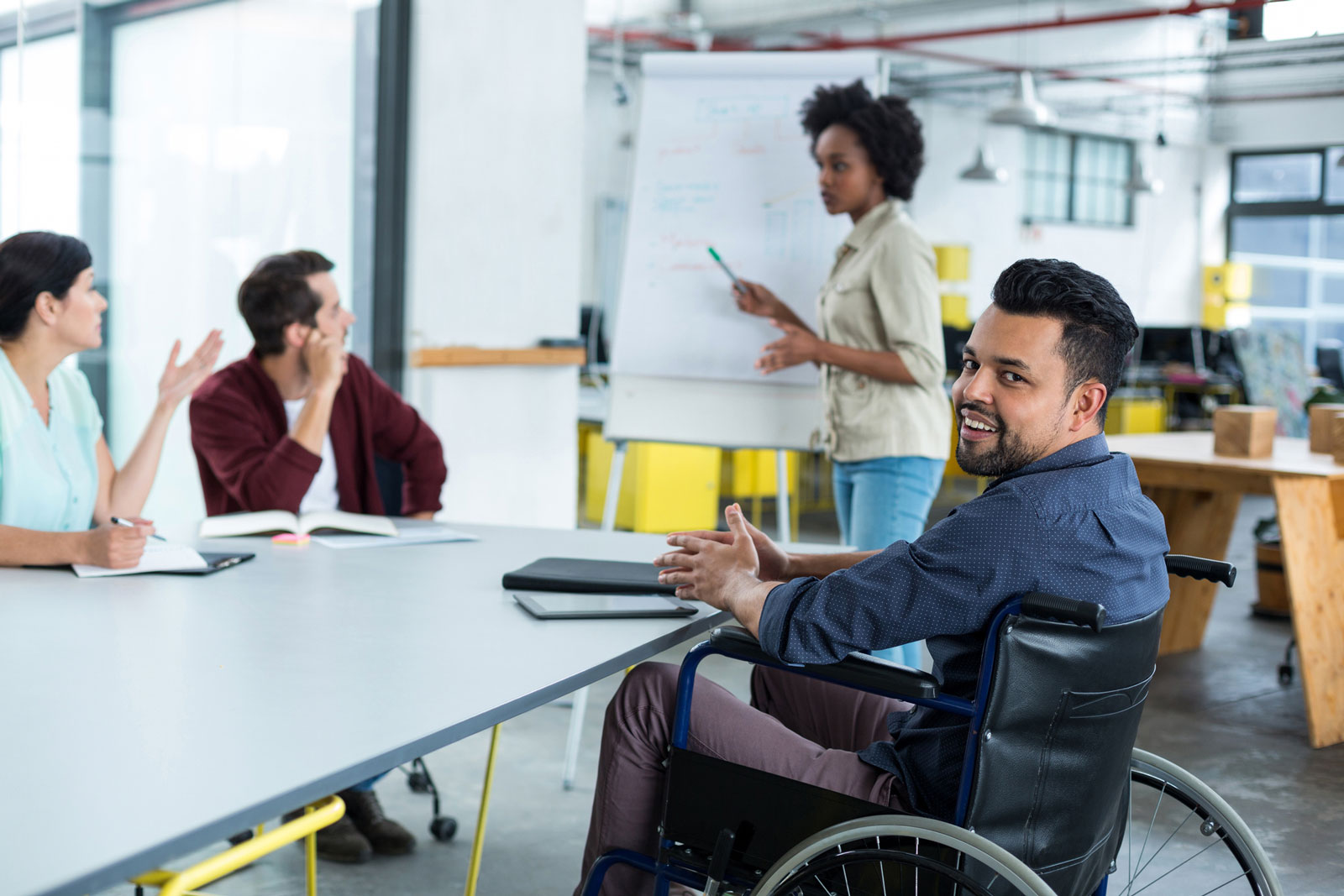 Business executive in wheelchair smiles during boardroom meeting