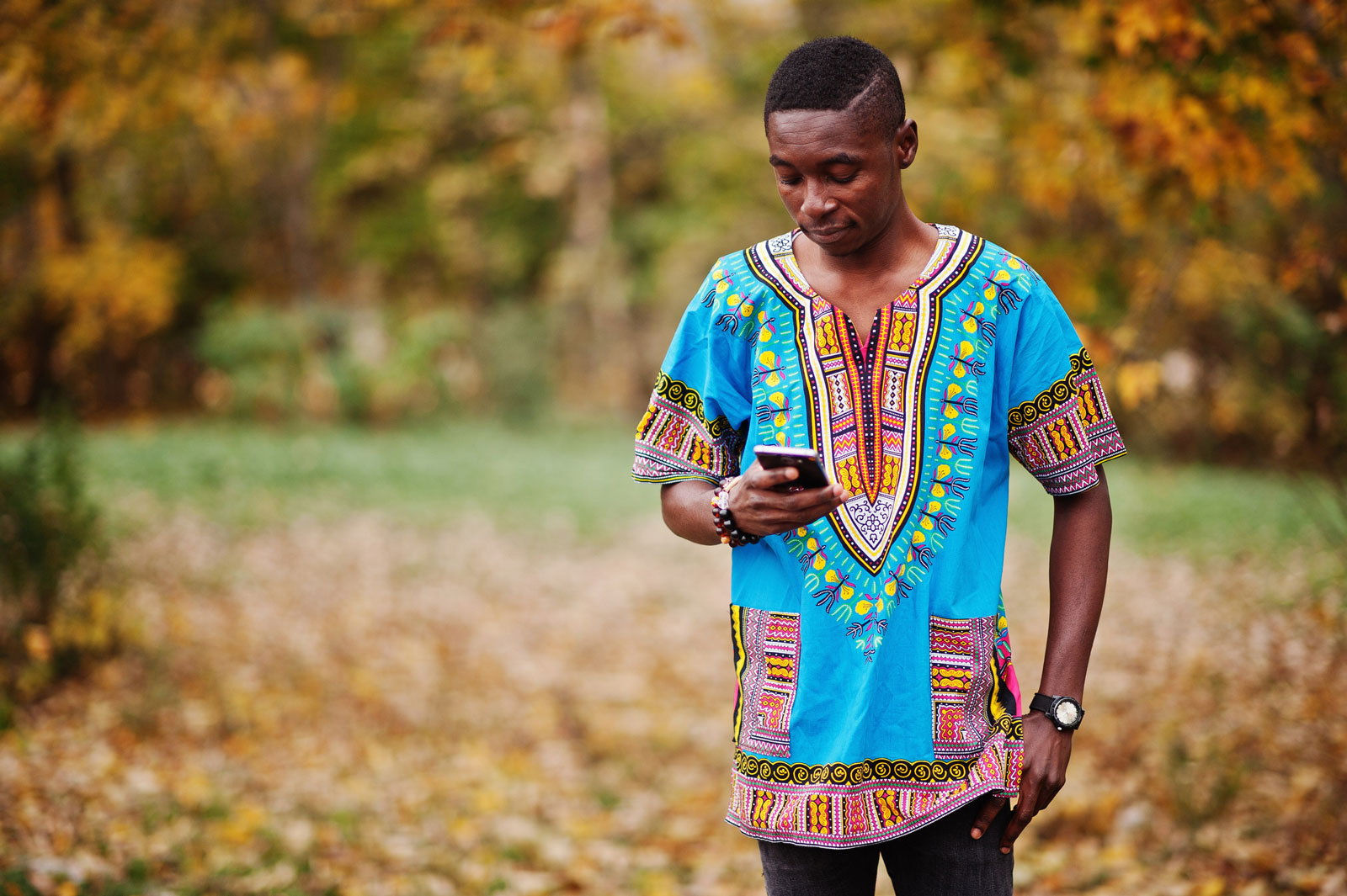 Young man standing outside holding cellphone