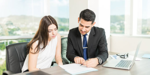 Male and female sitting at a desk looking at a piece of paper
