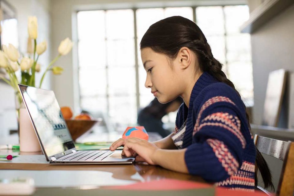 Young girl sitting and working on laptop at a desk