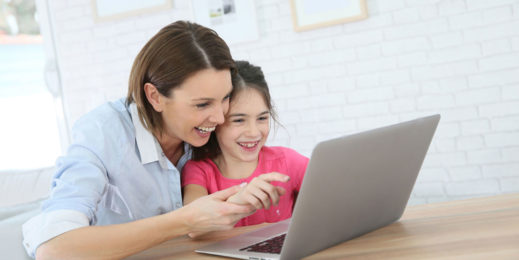 Mother assists her primary-school aged daughter during an online classroom session.