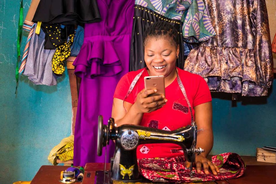 Woman shopkeeper smiling at smartphone.