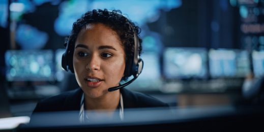 A young female security specialist on call consults the digital screen in front of her.