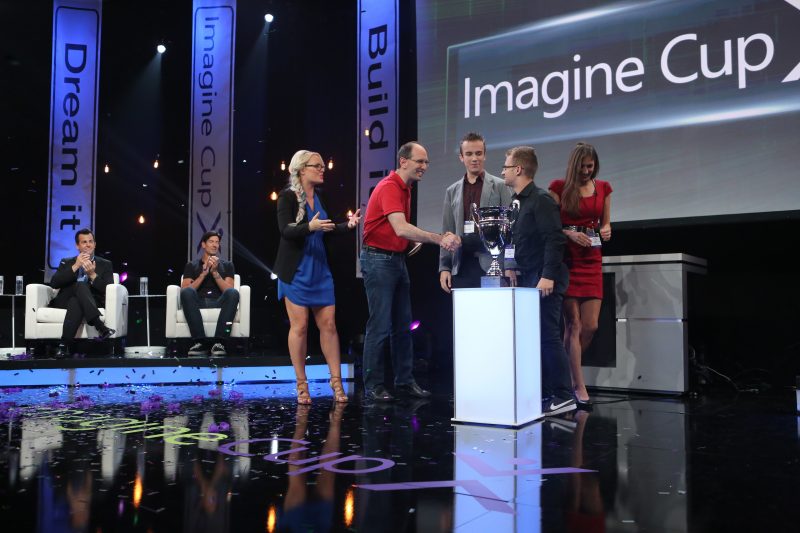 two men shake hands with the Imagine Cup trophy in the foreground