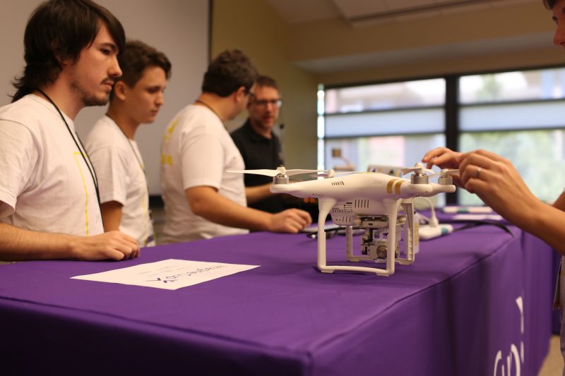 A drone sits on a table in front of four team members