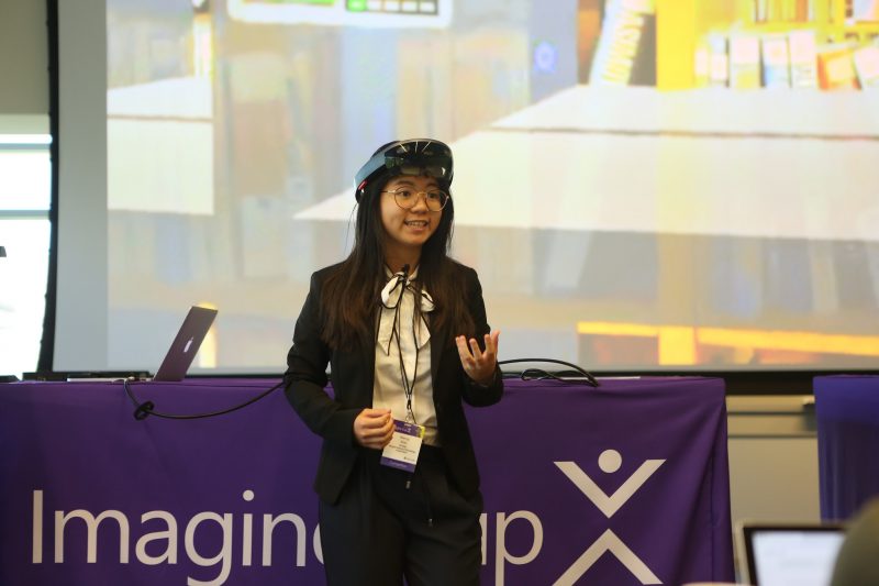 a woman stands with VR goggles on top of her head