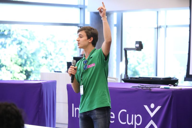 A team member holding a microphone speaks in front of judges