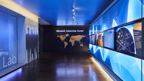 Photo of hallway with brightly lit displays and a sign at end of the hall that says Microsoft Cybercrime Center