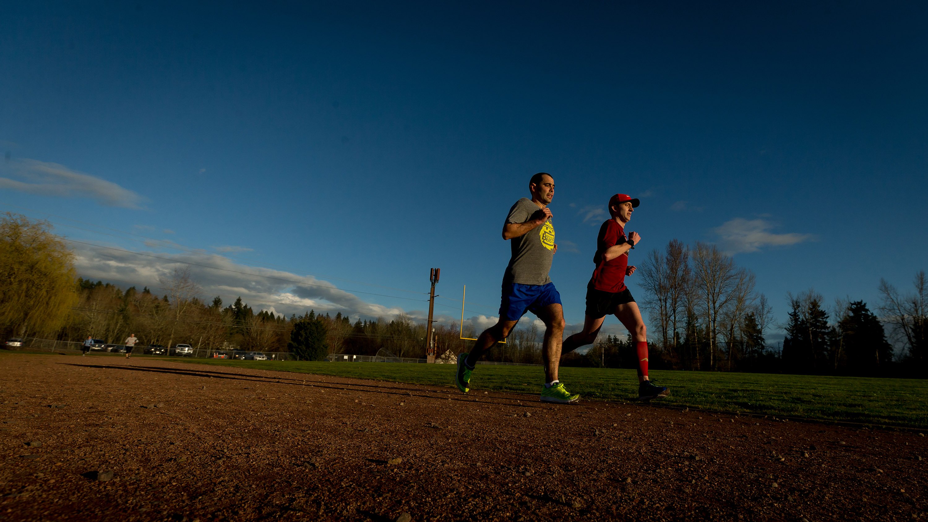 photo of two men running around a track in lockstep with determined looks on their faces