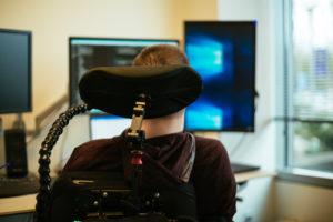 a man in a wheelchair views his computer monitors