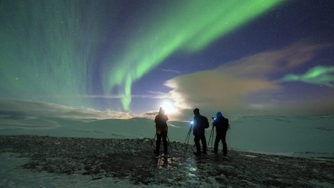 3 people watch the northern lights