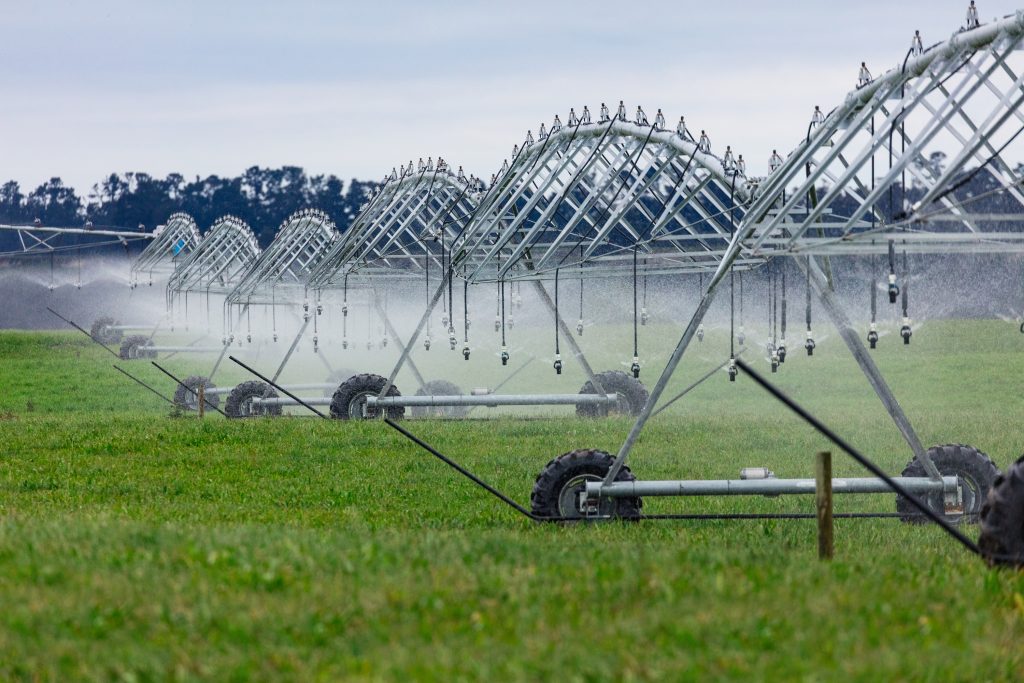 Large irrigation equipment sprays water on green field
