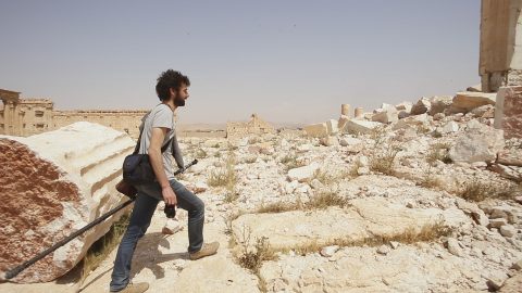 Man carries equipment while walking on ancient rubble