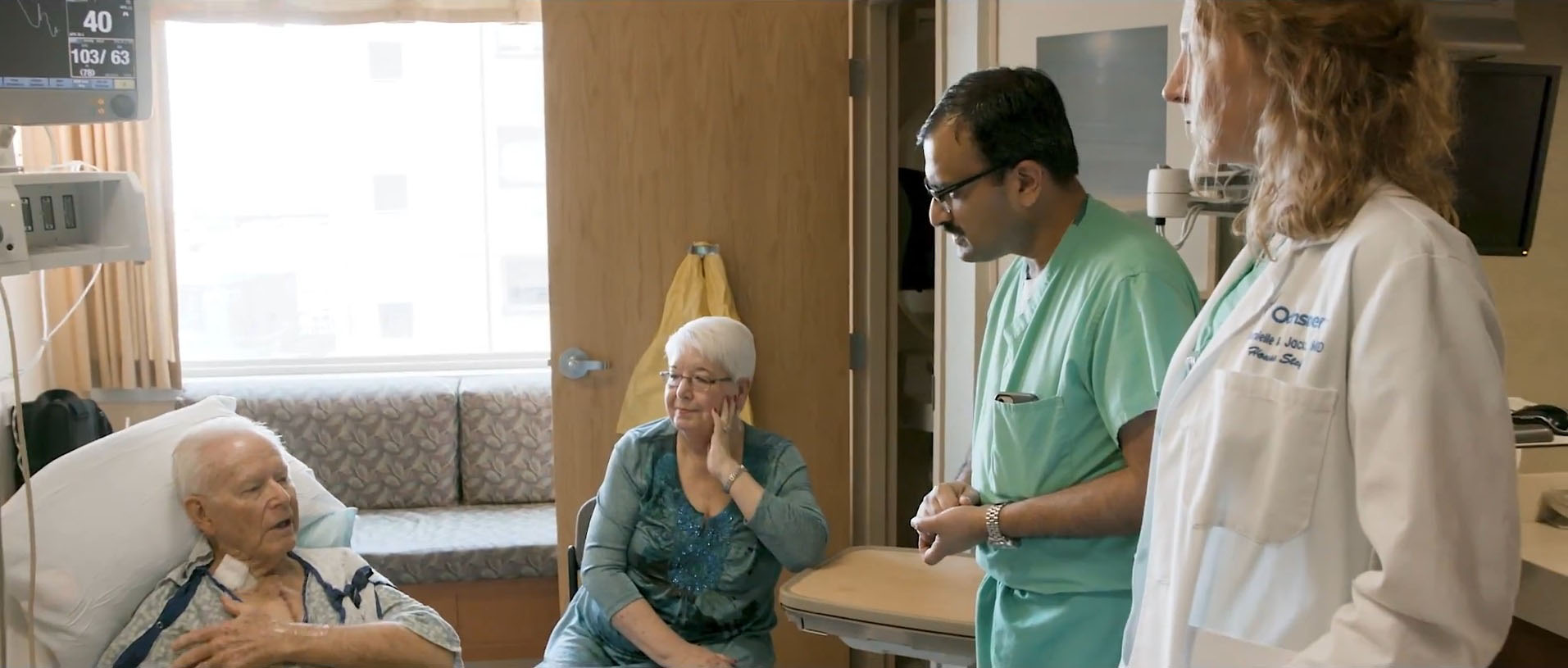 Two doctors talk to a patient and his wife in a hospital