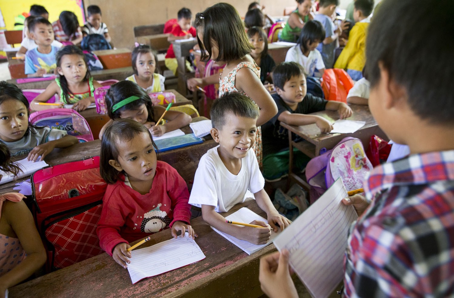 Young boy smiles in class among other students in a rural setting