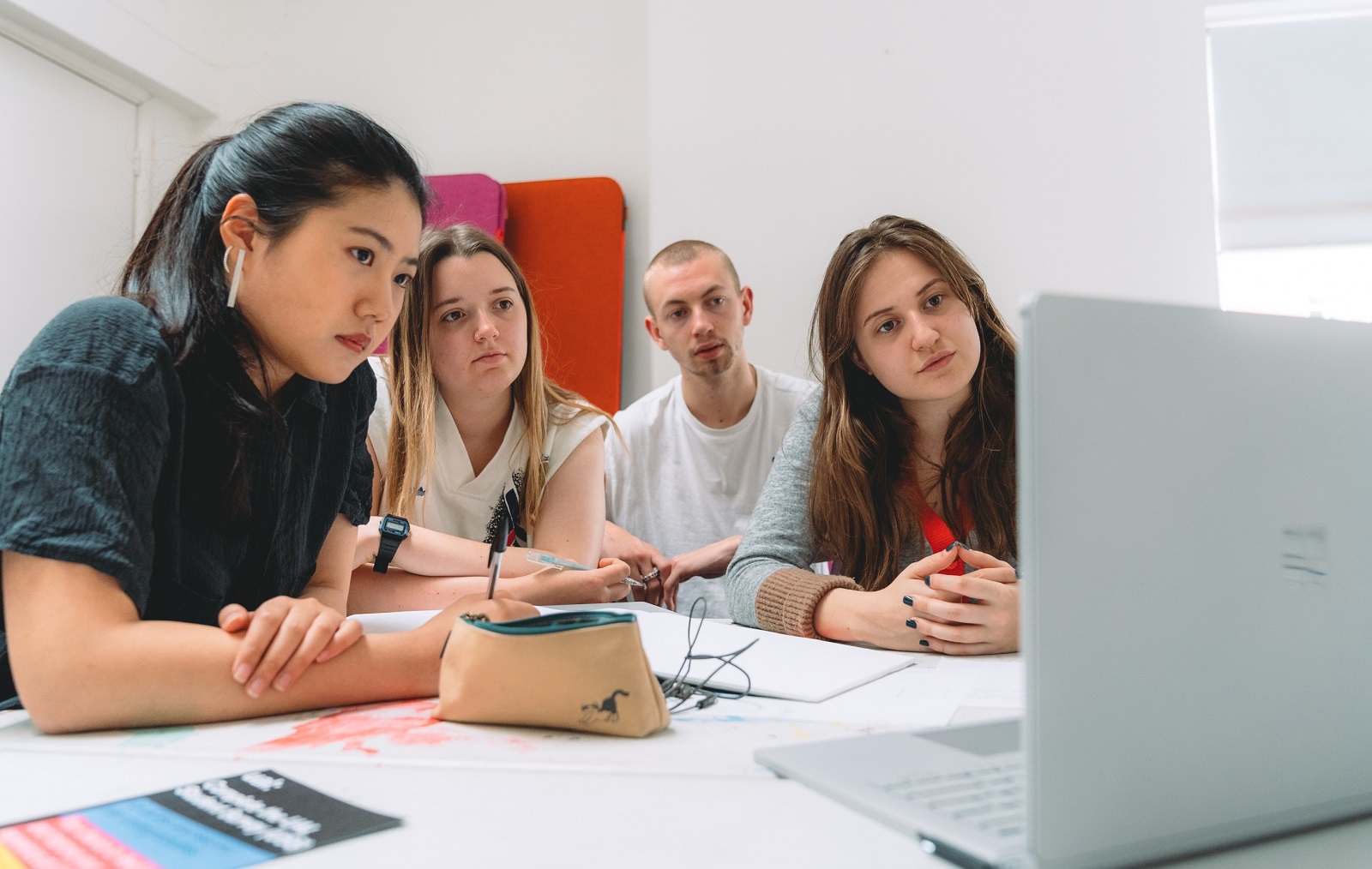 four students look at computer for a group project