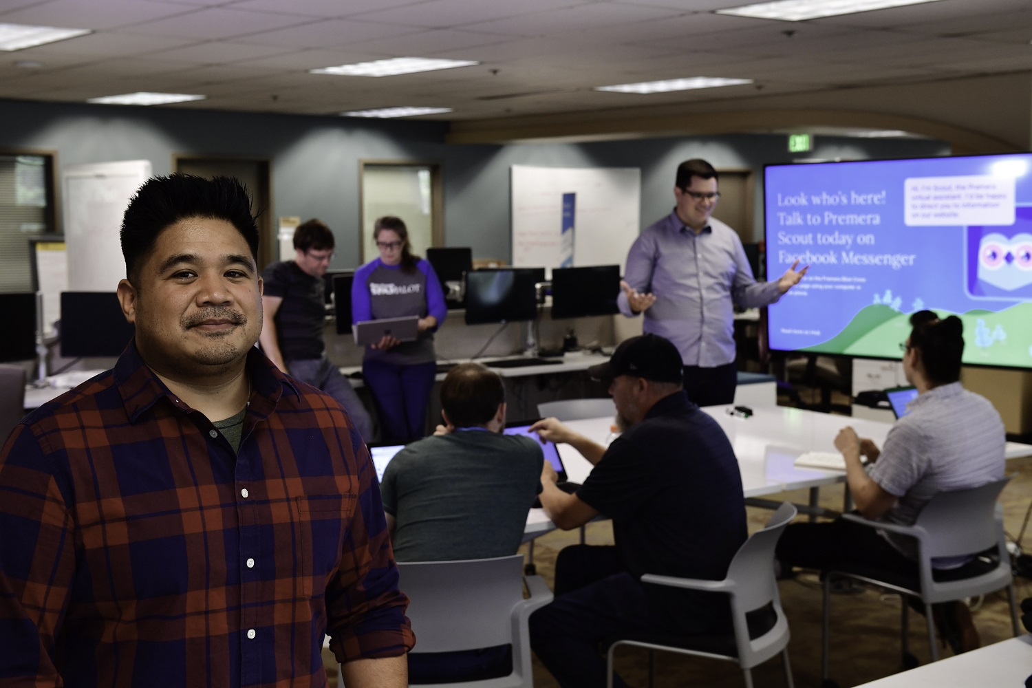 Neil Lazo stands in the foreground with employees in the background