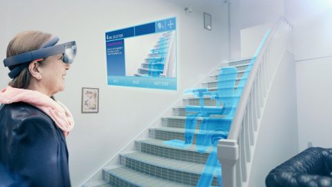 A woman uses a HoloLens device to visualize a stairlift in her home