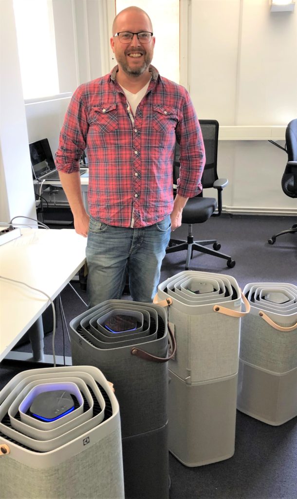 Andreas Larsson stands behind four Pure A9 air purifiers at Electrolux headquarters. 