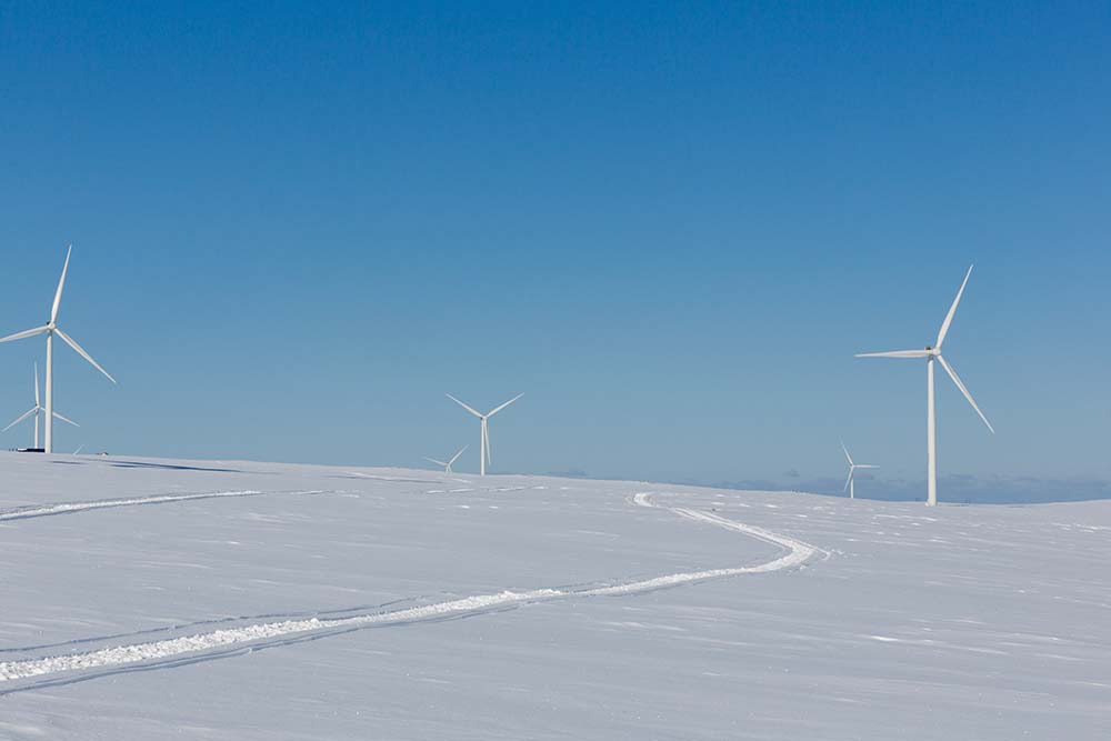 Wind turbines in a landscape of snow and blue sky