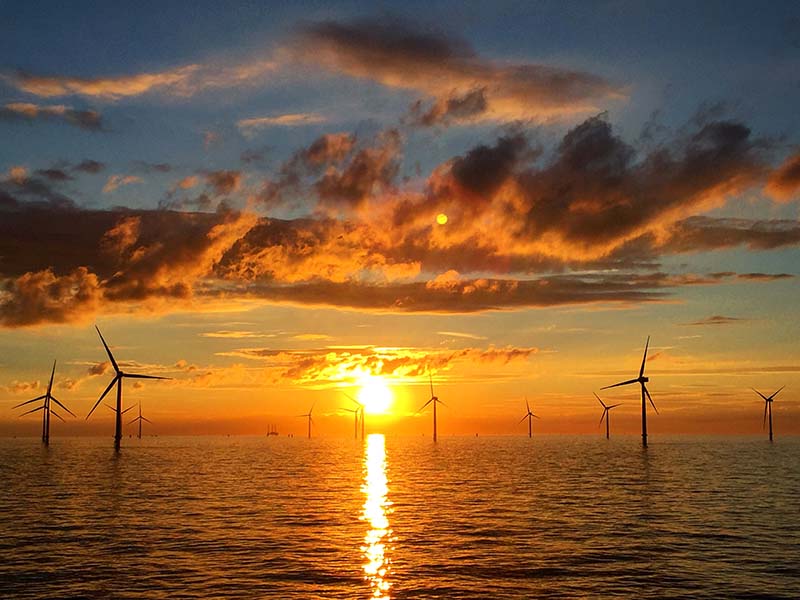 Offshore wind turbines pictured with a beautiful sunset