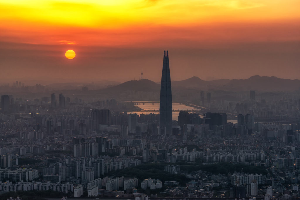 A smoggy skyline in Seoul, South Korea with the sun on the horizon. 