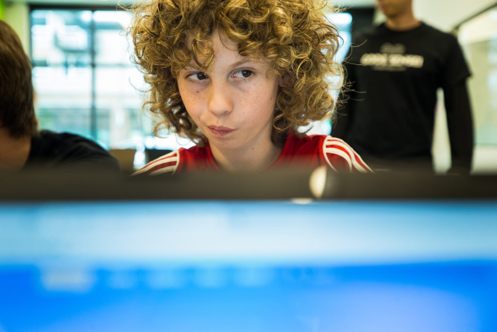 A boy stares into his computer screen while coding. 