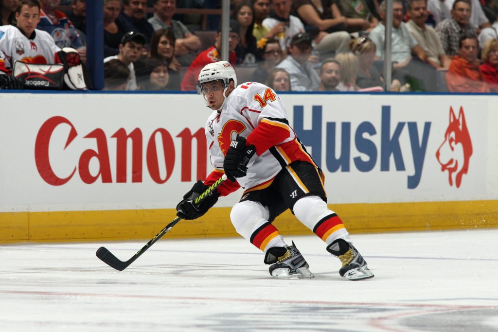 Theo Fleury skates during a game in Calgary, wearing the Flames uniform and a helmet.