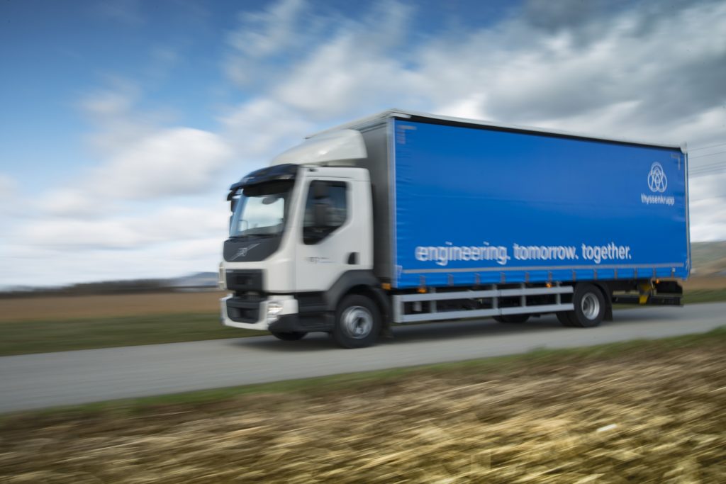 A thyssenkrupp truck travels on a highway.