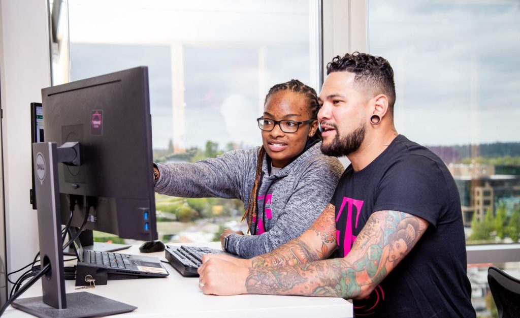 Two T-Mobile employees collaborate at a workstation.