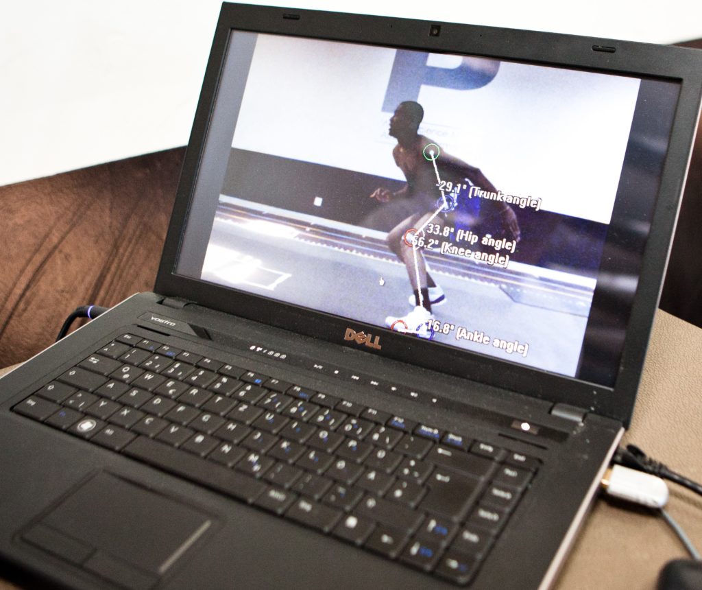 A laptop screen shows a player in mid-stride on a track and the movement data he is producing.