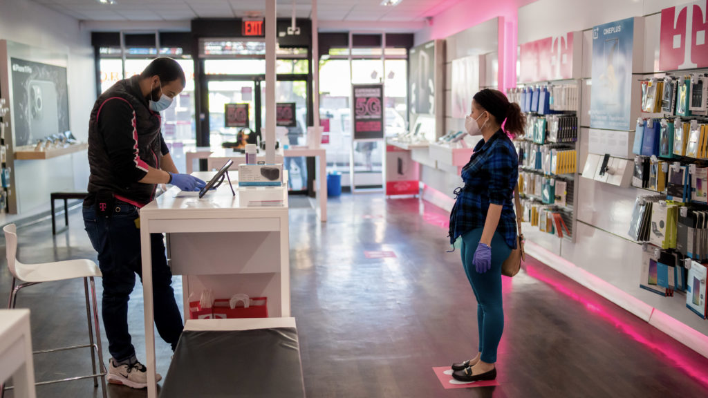A T-Mobile employee maintains a distance of 6 feet while helping a customer