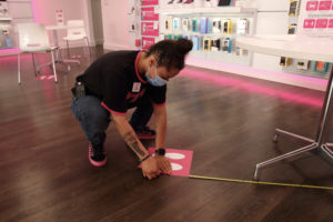A T-Mobile retail employee measures six feet of floor space